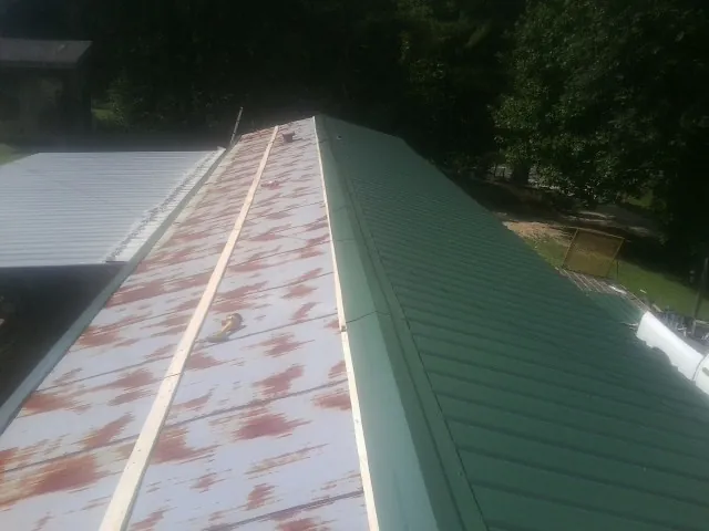 Old rusted panels beside newly installed green metal roofing — Wind Damage Roof Repair by Roofing Brothers in Bath